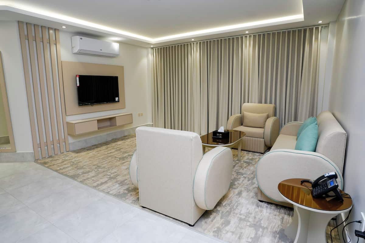 Una sala de estar moderna con un televisor de pantalla plana, sofás color beige, una mesa de centro y un equipo de aire acondicionado.