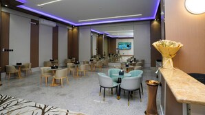 A hotel lobby with multiple seating areas, a reception desk, and a television screen in the background. - Nouf plaza (Al Duwadimi)