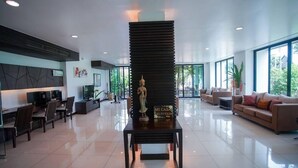 A spacious lobby with a central table displaying a statue, a sofa area, and a reception desk. - Sang Serene House (Chiang Mai)