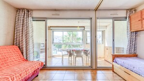 Une pièce dotée d’une porte-fenêtre coulissante donnant sur un balcon, d’un lit, d’un canapé et d’une petite table avec des chaises.