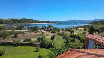 Un paisaje costero con vista despejada al mar, una zona con césped y un edificio con techo de tejas.