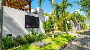 Une villa moderne dotée d’une pelouse bien entretenue, d’une enseigne portant le nom « ABAKOI Villa » et d’un chemin pavé.