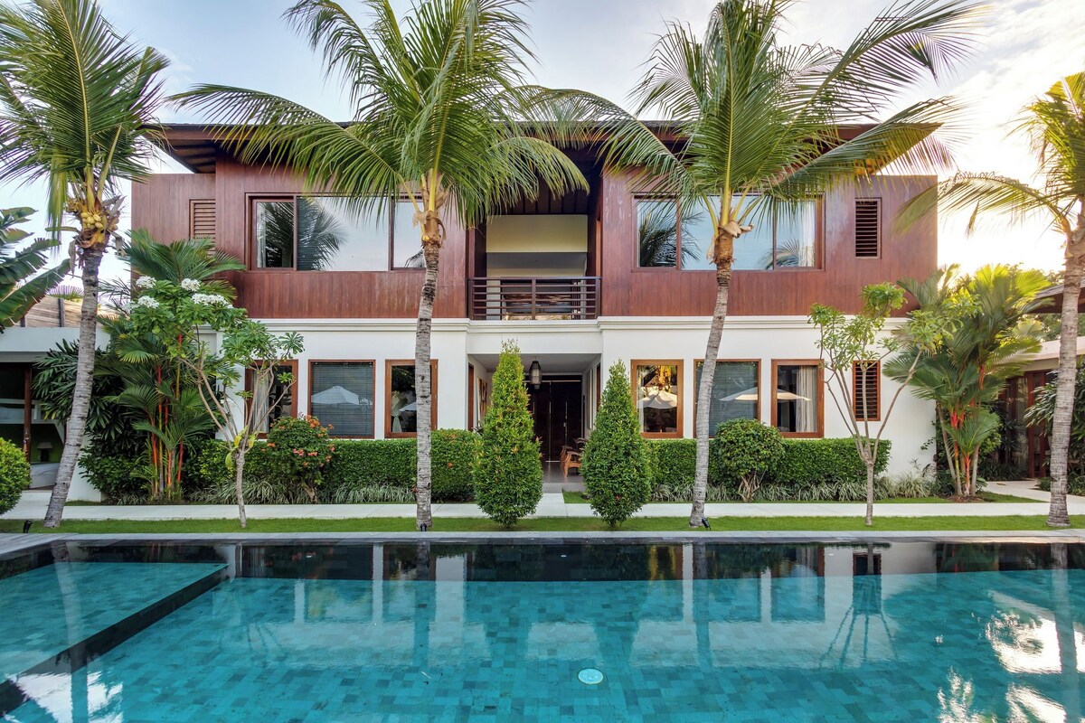 A modern two-story house with a swimming pool in front.