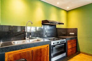 A kitchen with a stainless steel sink, a gas stove, and wooden cabinets. - Villa Abagram Seminyak (Seminyak)