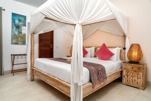 A four-poster canopy bed with a wooden frame and white bedding, a woven nightstand, and a painting on the wall. - Villa Abagram Seminyak (Seminyak)