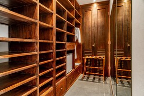 A wooden closet with multiple shelves and drawers, a small table, and a mirror. - Villa Abagram Seminyak (Seminyak)