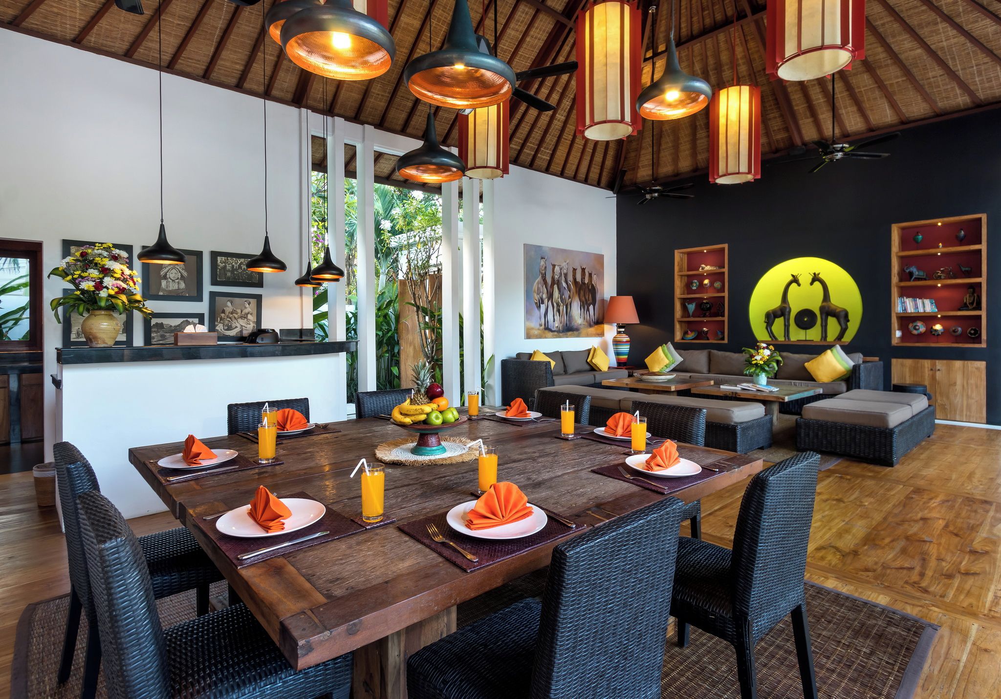 Un comedor con una mesa de madera preparada para cuatro personas, rodeada de sillas de mimbre.