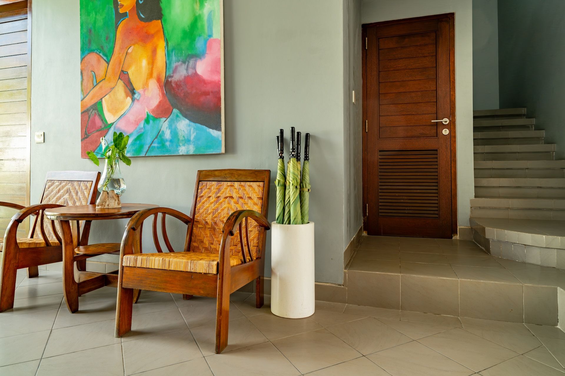 A dining area with wooden furniture, a painting on the wall, and a staircase leading to a door.