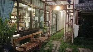 A patio area with wooden benches and a glass enclosure with a light fixture. - Trigong Residence (Chiang Mai)