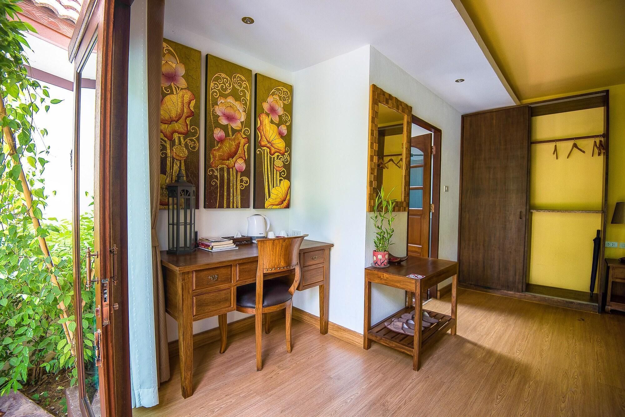 A room with a wooden desk, a mirror, and a potted plant.