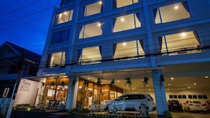 A multi-story hotel with a modern facade, large windows, and a visible entrance with outdoor seating. - Fa Dragon (Chiang Mai)