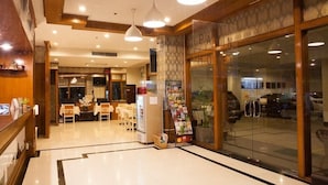 A hotel lobby with a reception desk, seating area, and a glass door entrance. - Fa Dragon (Chiang Mai)