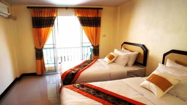 A hotel room with two beds, a balcony, and a window with curtains. - Manee Guest House (Chiang Mai)