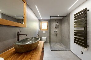 A modern bathroom with a large stone sink, a glass-enclosed shower, and a wooden vanity. - 4006 Villa Ulrich 2 (St. Gallenkirch)