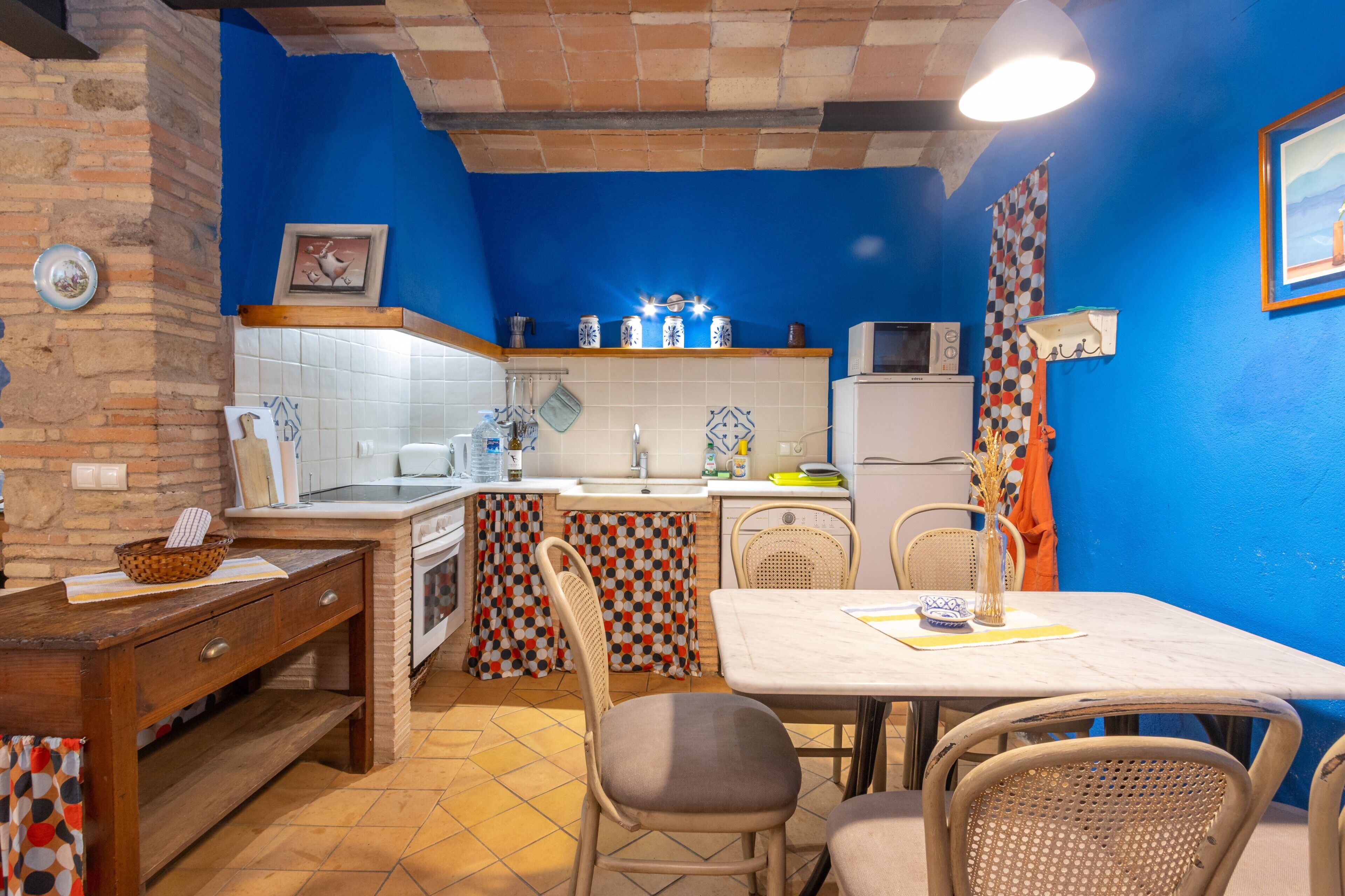 Cocina compacta con comedor, que incluye un salpicadero de azulejos, un microondas y un refrigerador.