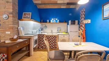 Cocina compacta con comedor, que incluye un salpicadero de azulejos, un microondas y un refrigerador.
