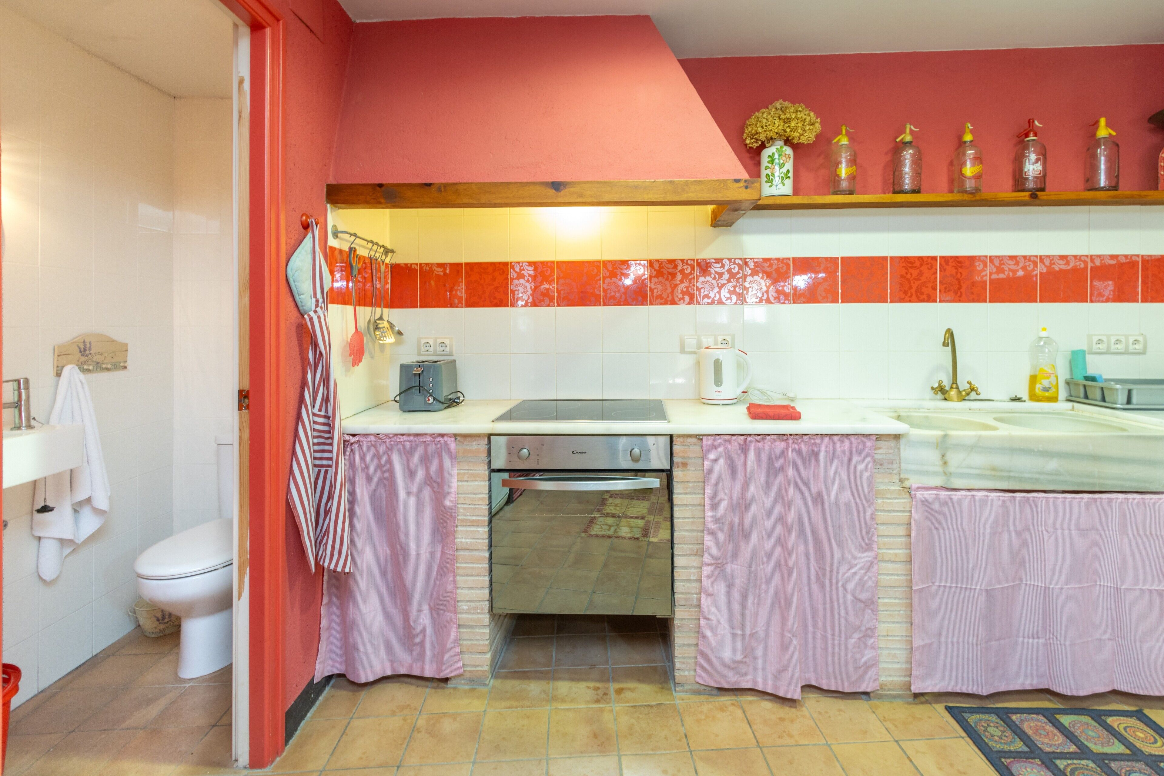 Une cuisine avec un plan de travail blanc, un four encastré et un crédence rouge.