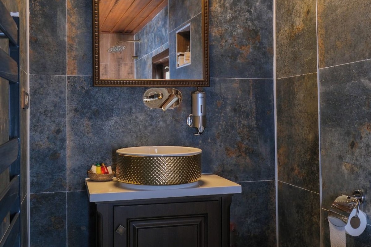 A bathroom with a round sink, a mirror with a gold frame, and a toilet.