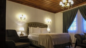 Une chambre à coucher avec un grand lit, deux lampes de chevet, un fauteuil et un lustre.