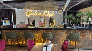 Un espace bar avec un panneau néon, un comptoir, des chaises et une table avec un set de table.