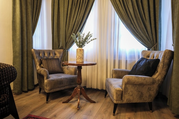 A room with two armchairs, a small round table, and a vase with greenery. - Gülce Köşk Otel & Restaurant (Amasya)