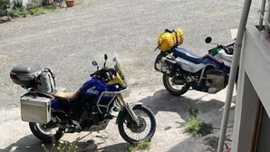 En motorcykel parkerad utanför en byggnad, med en ramp av betong som leder fram till en dörr.