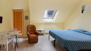A compact room with a bed, a chair, a table, and a skylight. - Apartment "Les Moulins - Studio 1" with Balcony and Wi-Fi (Cherbourg en Cotentin)