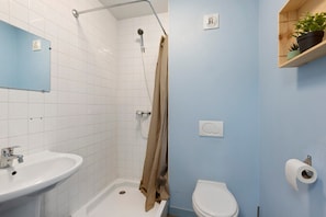 Ein Badezimmer mit Dusche, Toilette, Waschbecken und einem Handtuchhalter.