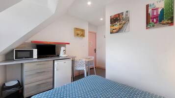 A compact room with a kitchenette, a bed, a small table, and chairs.