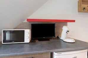 Eine Küchenzeile mit Mikrowelle, Fernseher und Kaffeemaschine auf einer Arbeitsfläche.