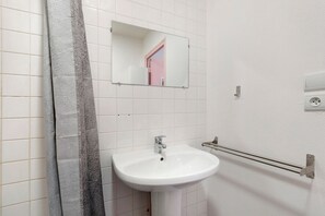Ein Badezimmer mit einem weißen Waschbecken, einem Spiegel und einem Handtuchhalter.