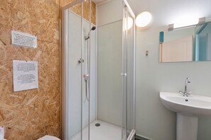 Ein Badezimmer mit einer Duschkabine, einem Waschbecken und zwei Hinweisschildern an der Wand.