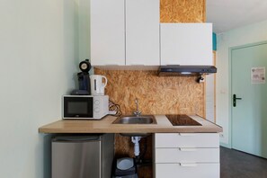 Une petite cuisine équipée d’un four à micro-ondes, d’une machine à café et d’un petit évier.