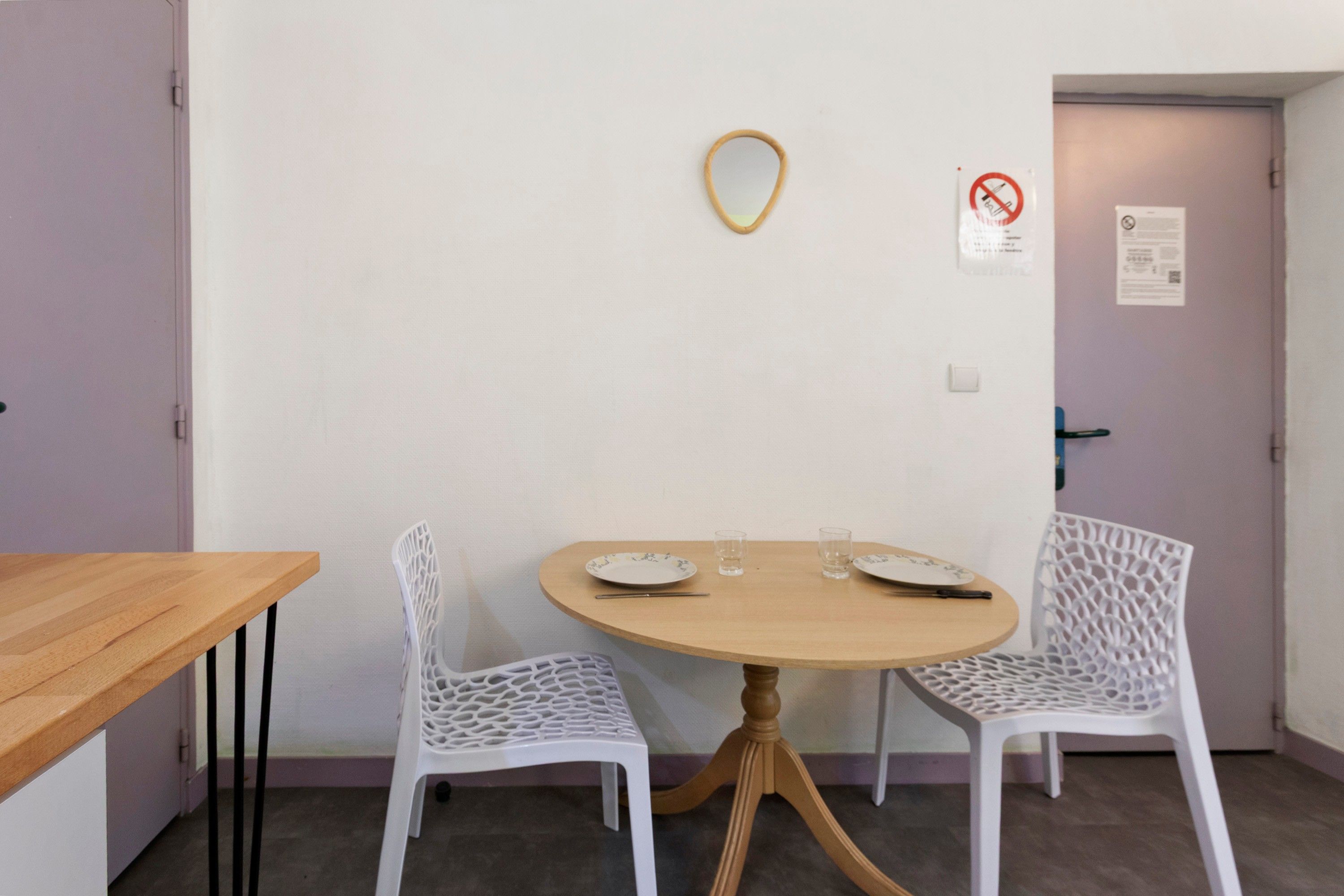 Een klein eetgedeelte met een ronde tafel, twee witte stoelen en een houten bijzettafeltje.