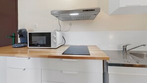Una cucina con un forno a microonde, una macchina per il caffè e un lavello.