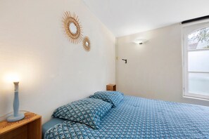 Quarto com cama, mesa de cabeceira, decoração na parede, janela e porta.