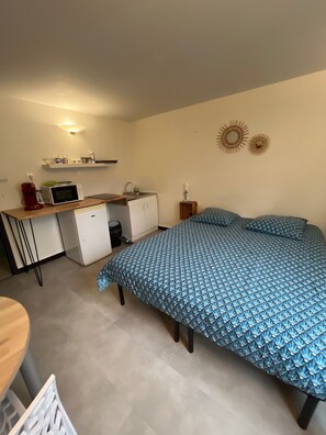 Une chambre compacte comprenant un lit, un petit bureau avec un micro-ondes et une chaise.