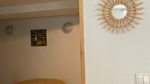 A room with a round table, two chairs, a wall-mounted mirror, and a framed sign. - Apartment 'Les Moulins - 8' with Wi-Fi (Cherbourg en Cotentin)