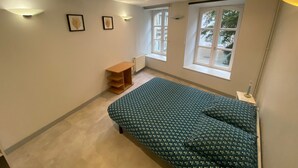 A bedroom with a bed, a radiator, a window, and a shelf. - Apartment 'Les Moulins - 8' with Wi-Fi (Cherbourg en Cotentin)
