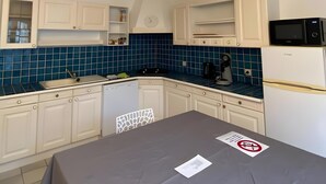 A kitchen with white cabinets, a blue tiled backsplash, a stainless steel sink, a microwave, and a refrigerator. - Apartment 'Les Moulins - T2 - 4' with Wi-Fi (Cherbourg en Cotentin)
