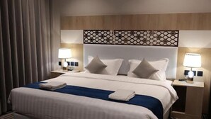 Een hotelkamer met een bed, twee nachtkastjes en een hoofdbord met een geometrisch patroon.