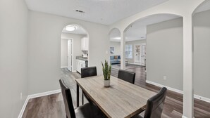 A dining area with a wooden table, black chairs, and a potted plant. There are white walls and a ceiling with a recessed light. - Spacious condo near Atlanta with great sleep (Stockbridge)