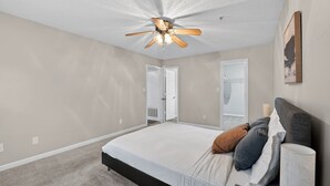 A bedroom with a bed, a ceiling fan, and a door leading to another room. - Spacious condo near Atlanta with great sleep (Stockbridge)