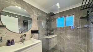 Une salle de bain moderne avec un grand miroir, une douche et une fenêtre.