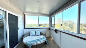 Une chambre à coucher avec un lit rond, de grandes fenêtres et une vue sur l’extérieur.