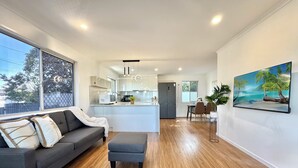 Une cuisine moderne avec des meubles blancs, un îlot central et un coin repas comprenant une table et des chaises.