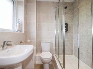 A bathroom with a white sink, toilet, and glass shower enclosure. - Blissful Ocean Breeze (Perranporth)