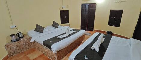 A hotel room with two beds, a marble bedside table, a coffee maker, and a wardrobe.