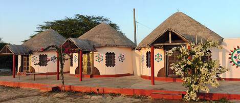 Une rangée de huttes traditionnelles aux toits de chaume et aux murs ornés de motifs géométriques colorés.
