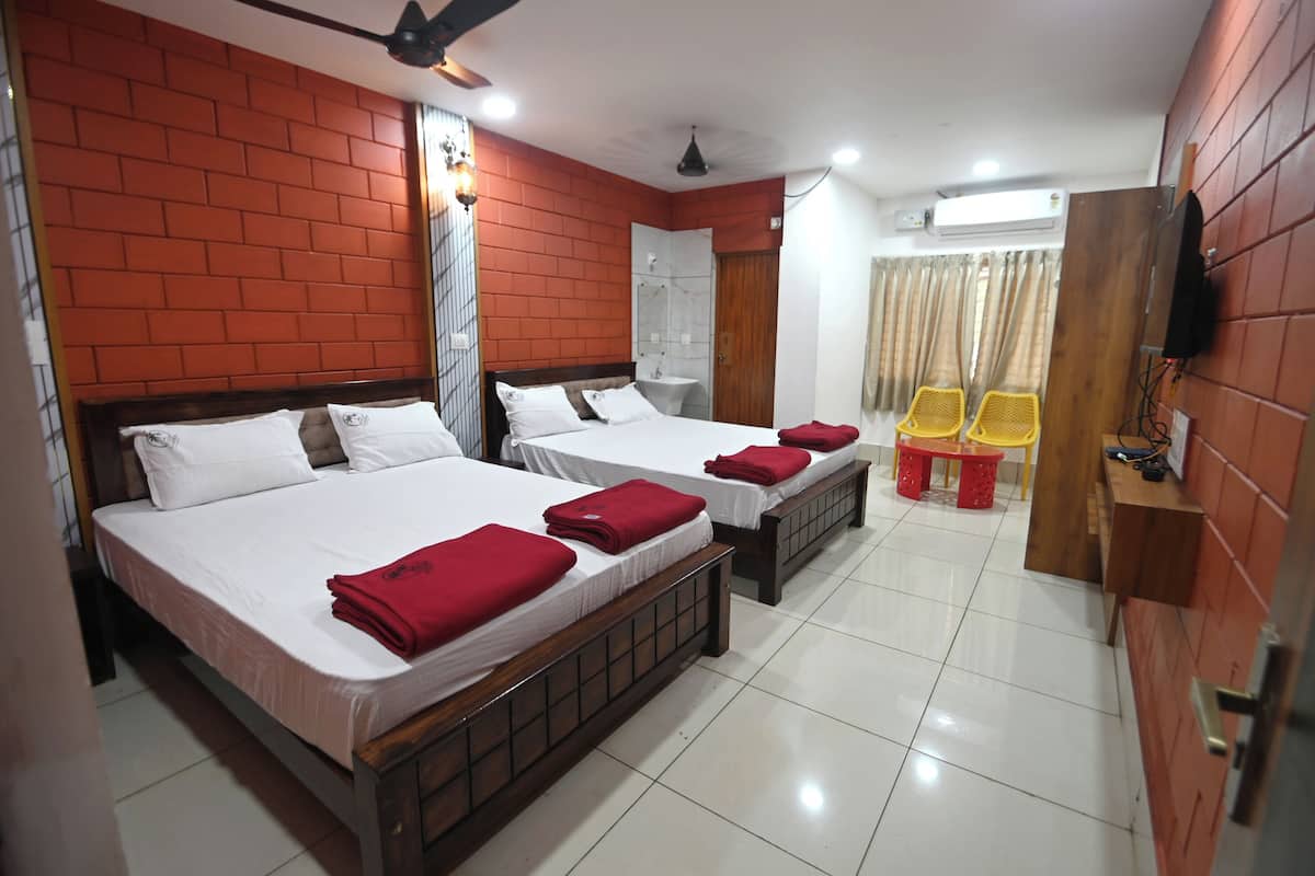 A hotel room with two beds, a TV, a ceiling fan, and a small table with chairs.
